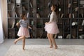 Overjoyed older and younger sisters dressed in pettiskirts dance together