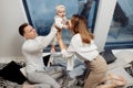 Overjoyed parents with adorable baby girl having fun at home, smiling, caring father lift little daughter in air, young