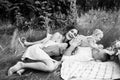 Overjoyed parents with adorable daughter relaxing on blanket at the park, smiling, hugging, lovely family having a Royalty Free Stock Photo