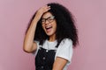Overjoyed pleased curly haired woman keeps hand on forehead, laughs from happiness, understands she did something funny, wears Royalty Free Stock Photo