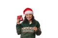 Overjoyed pretty woman in Santa hat and Xmas patterned green sweater, holds Christmas gift isolated on white background Royalty Free Stock Photo