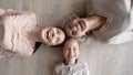 Overjoyed three generations family lying on warm wooden heated floor.