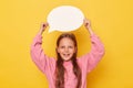 Overjoyed smiling cheerful little girl with long hair holding empty speech bubble over her head wearing pink sweatshirt isolated