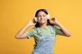 Overjoyed teen school girl listening to music in earphones with positive delighted face expression