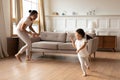 Overjoyed ethnic mother and daughter running playing at home