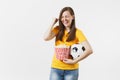 Overjoyed woman football fan in yellow uniform holding soccer ball, popcorn doing winner gesture saying Yes isolated on