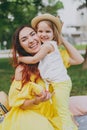Overjoyed woman in yellow dress play in park amuse and hug, embrace with little child baby girl hold soap bubble blower Royalty Free Stock Photo