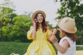 Overjoyed woman in yellow clothes play in park have fun, amuse with little cute child baby girl hold soap bubble blower Royalty Free Stock Photo