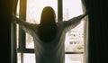 Overjoyed young beautiful woman standing by bedroom and opening curtains look in window distance meet welcome new day. Royalty Free Stock Photo