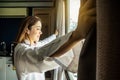 Overjoyed young beautiful woman standing by bedroom and opening curtains look in window distance meet welcome new day. Royalty Free Stock Photo