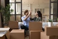 Overjoyed young couple celebrating relocation, unpacking boxes, giving high five