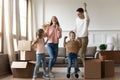 Overjoyed young couple having fun with daughters in new apartment. Royalty Free Stock Photo