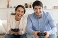 Overjoyed young couple playing video game on console at home