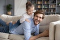 Overjoyed young daddy holding laughing little child daughter on back. Royalty Free Stock Photo