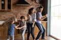 Overjoyed young family with kids dance in kitchen