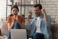 Overjoyed young husband wife scream yes as winners by laptop