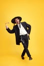 Overjoyed young Jewish man singing and dancing holds groggers in hands against sunny yellow background. Purim Royalty Free Stock Photo