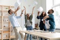 Overjoyed young multiracial business team throwing paper documents in air. Royalty Free Stock Photo