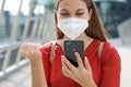 Overjoyed young woman with fist up and KN95 protective mask reading message on mobile phone expressing happiness about great news