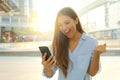 Overjoyed young woman reading message from friend on mobile expressing happiness about great news. Emotional female excited with