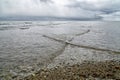 Overlapping, intersecting waves on seashore with dramatic cloudy sky. Natural background, pattern, texture of water. Interference