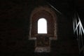 Selective blur on a light and shadow of a medieval castle window with a window seat in a dark European castle Royalty Free Stock Photo