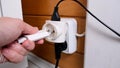 Overloaded outlet with an extension and many sockets plugged in, a hand plugging a socket into the outlet, risk of fire and short Royalty Free Stock Photo