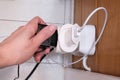 Overloaded outlet with an extension and many sockets plugged in, a hand plugging a socket into the outlet, risk of fire and short Royalty Free Stock Photo