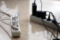 Overloaded power boards. Power strips with different electrical plugs on white floor