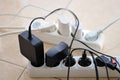 Overloaded power boards. Power strips with different electrical plugs on white floor