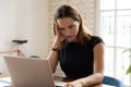 Upset businesswoman sitting at desk reading on laptop unpleasant message