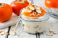 Overnight breakfast oatmeal with persimmons, table scene on rustic wood