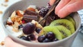 Overnight oatmeal bowl with kiwi, chocolate, berries and tahini, eating, close up.
