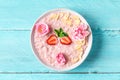 Overnight oats with fresh strawberries, almonds and mint in a bowl with rose flowers on blue wooden table