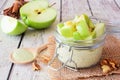 Overnight oats with matcha and green apples in a jar with a rustic white wood background