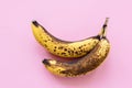 Overripe bananas on pink background