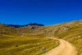 Oversaturated. Old mountain road, rocky landscape, mountain top in the background with blue sky and moon. Bjelasnica Mountain,