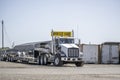 Oversize loader big rig powerful semi truck tractor with oversize load sign on the roof with empty step deck semi trailer standing Royalty Free Stock Photo