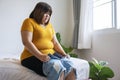 Oversize young woman want to wear short jeans. Overweight female sitting on the bed holding pants jeans worried about weight gain Royalty Free Stock Photo