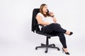 Oversized business woman sitting in office leather chair looking pensively to the side isolated on white studio Royalty Free Stock Photo