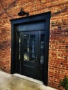 Oversized painted black door on an old brick building wall.