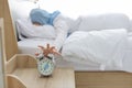 Oversleeping asian muslim woman wearing white sleepwear lying on bed, missing ring of alarm clock waking up. Royalty Free Stock Photo
