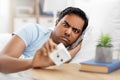 Overslept indian man in bed looking at alarm clock Royalty Free Stock Photo