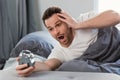Overslept Man Holding Alarm Clock Lying In Bed At Home Royalty Free Stock Photo