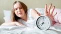 Overslept young woman awake in pajamas turns off alarm clock in hurry. Morning routine and wake up late from alarm clock