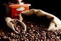Overturned bag full of coffee beans on black with spatula and mill Royalty Free Stock Photo