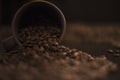 Overturned brown coffee cup and roasted coffee beans on dark kitchen table Royalty Free Stock Photo