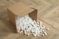 Overturned cardboard box with styrofoam cubes on wooden floor Royalty Free Stock Photo