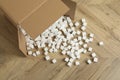 Overturned cardboard box with styrofoam cubes on wooden floor, above view Royalty Free Stock Photo