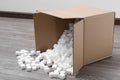 Overturned cardboard box with styrofoam cubes on wooden floor indoors Royalty Free Stock Photo